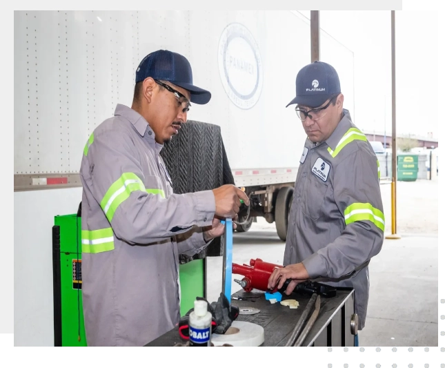 Two men working on a truck in an industrial setting.